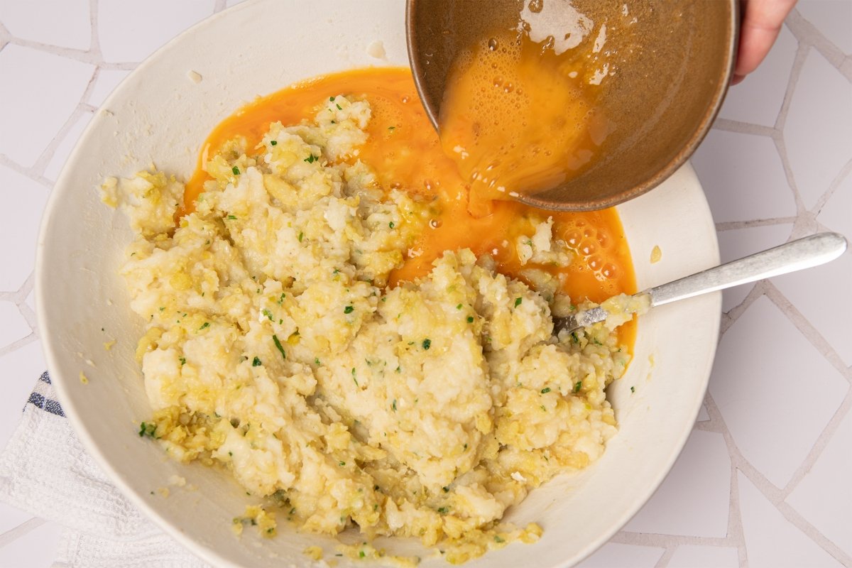 Añadiendo huevos a la masa del pastel de bacalao
