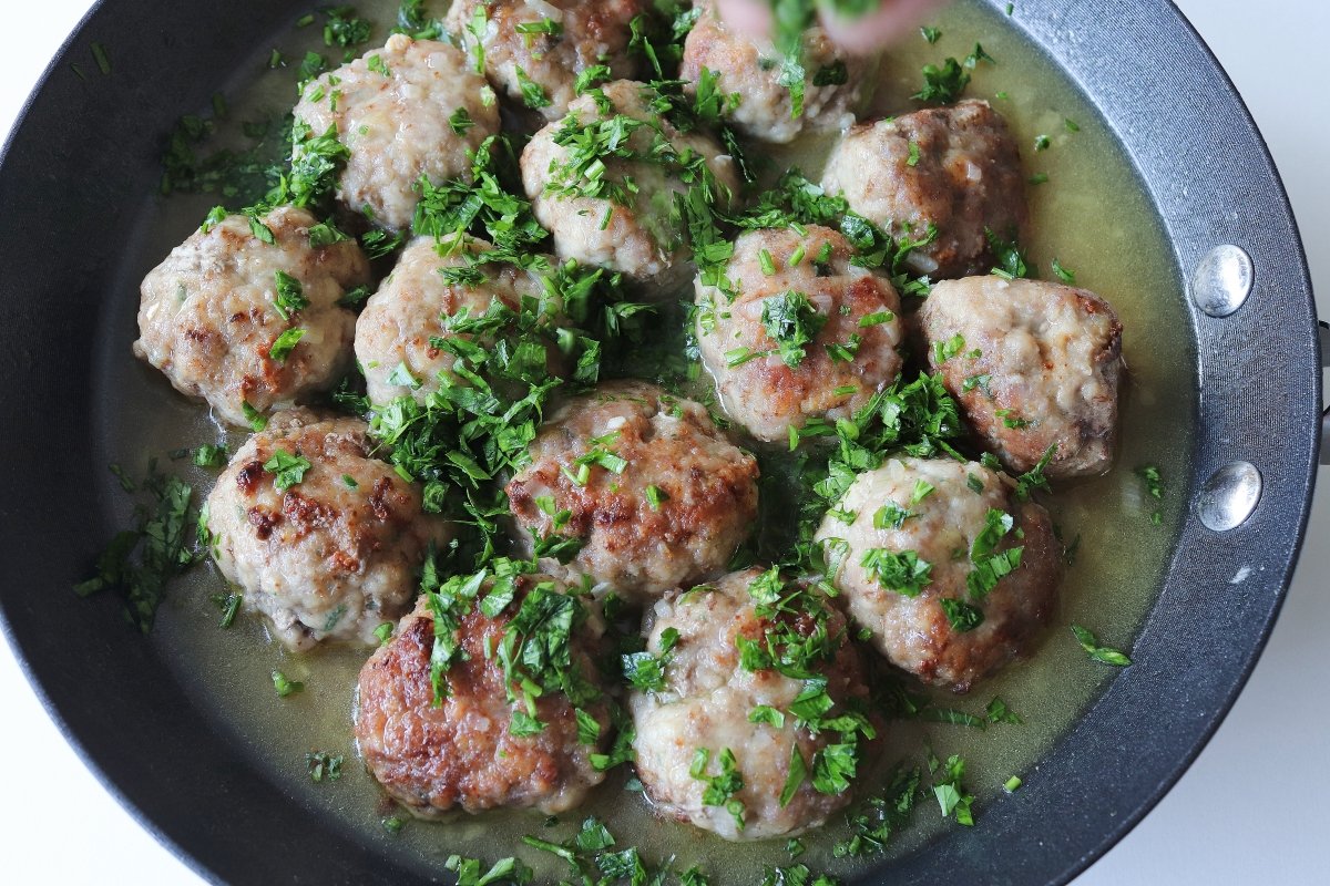 Añadir perejil a las albóndigas de carne en salsa verde