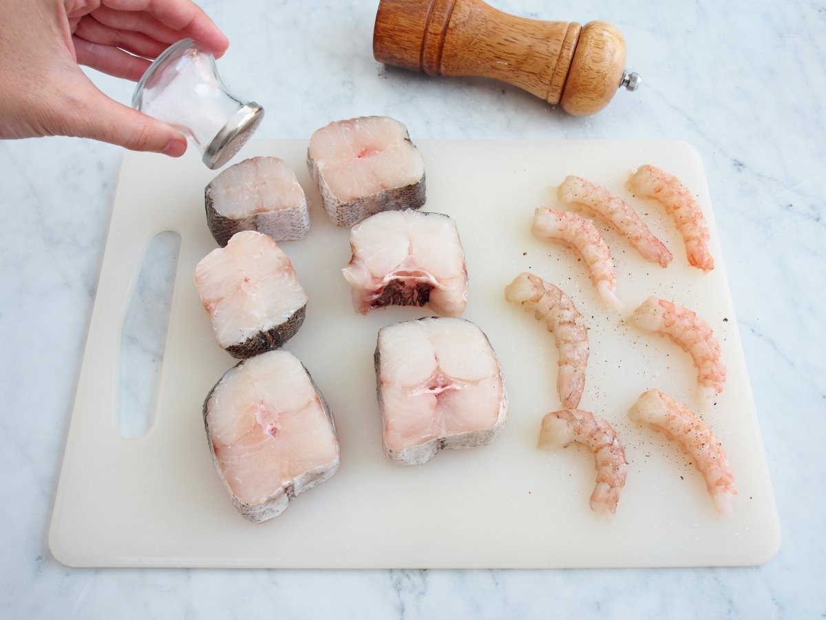 Añadir sal a la merluza y las gambas para la merluza a la marinera