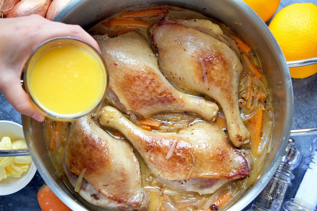 Echando el zumo de naranja en la olla del pato a la naranja