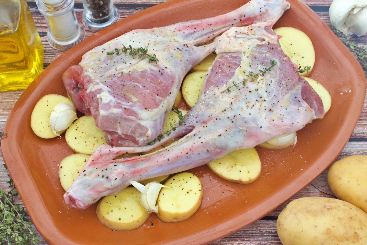 El cabrito sobre la bandeja de barro para seguir haciendo el cabrito al horno con patatas