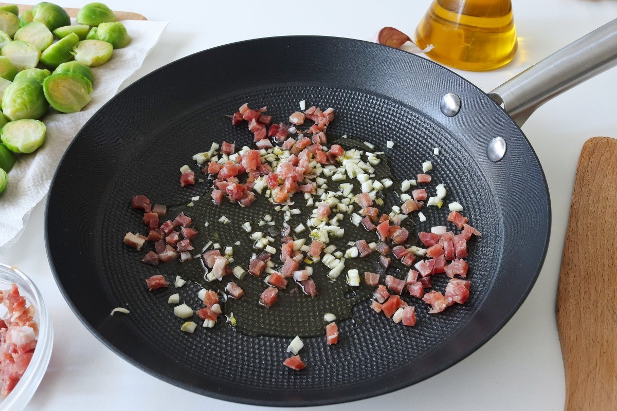 Freír los ajos y el jamón para las coles de Bruselas salteadas